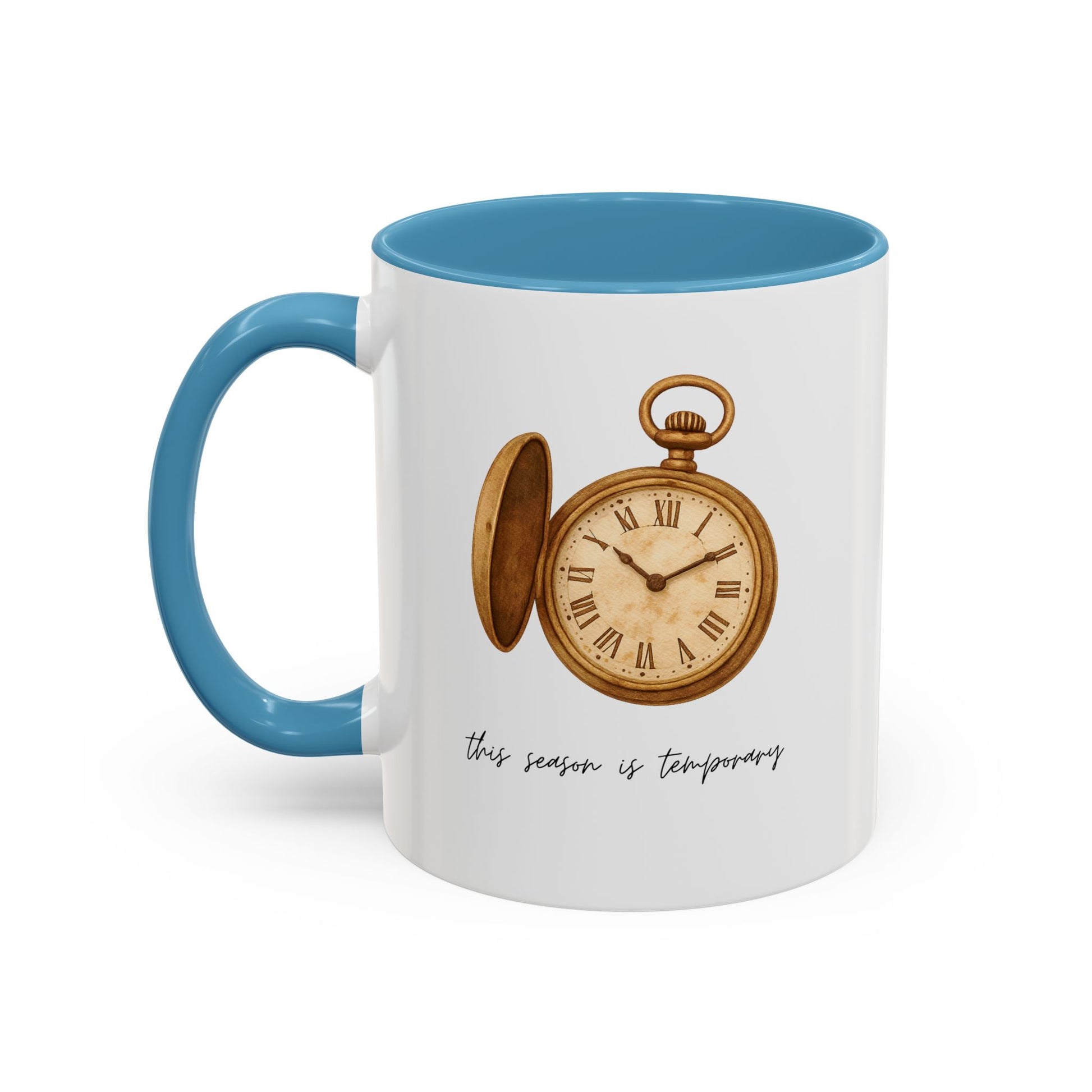 A white ceramic mug with a blue handle and blue interior, featuring a vintage-style illustration of an open gold pocket watch and the text 'this season is temporary' on the front.