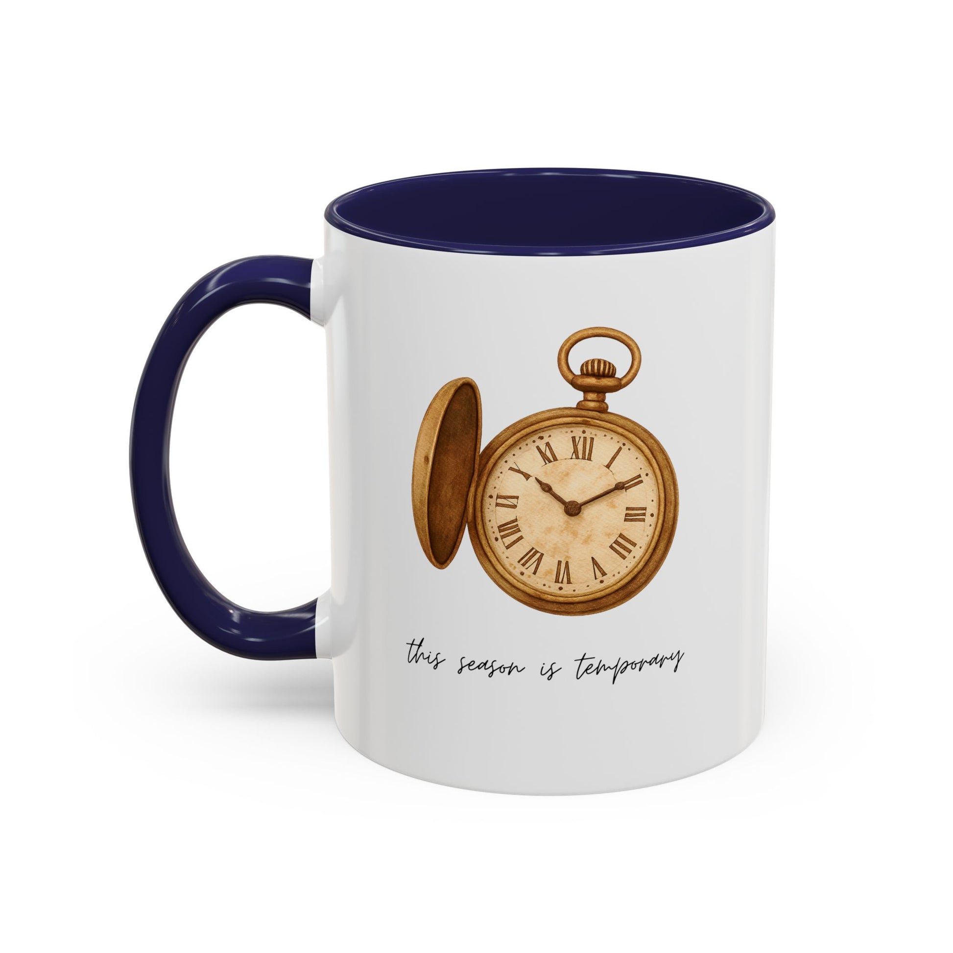 A white ceramic mug with a dark navy blue handle and interior, featuring a vintage-style illustration of an open gold pocket watch and the cursive text 'this season is temporary' printed on the front.